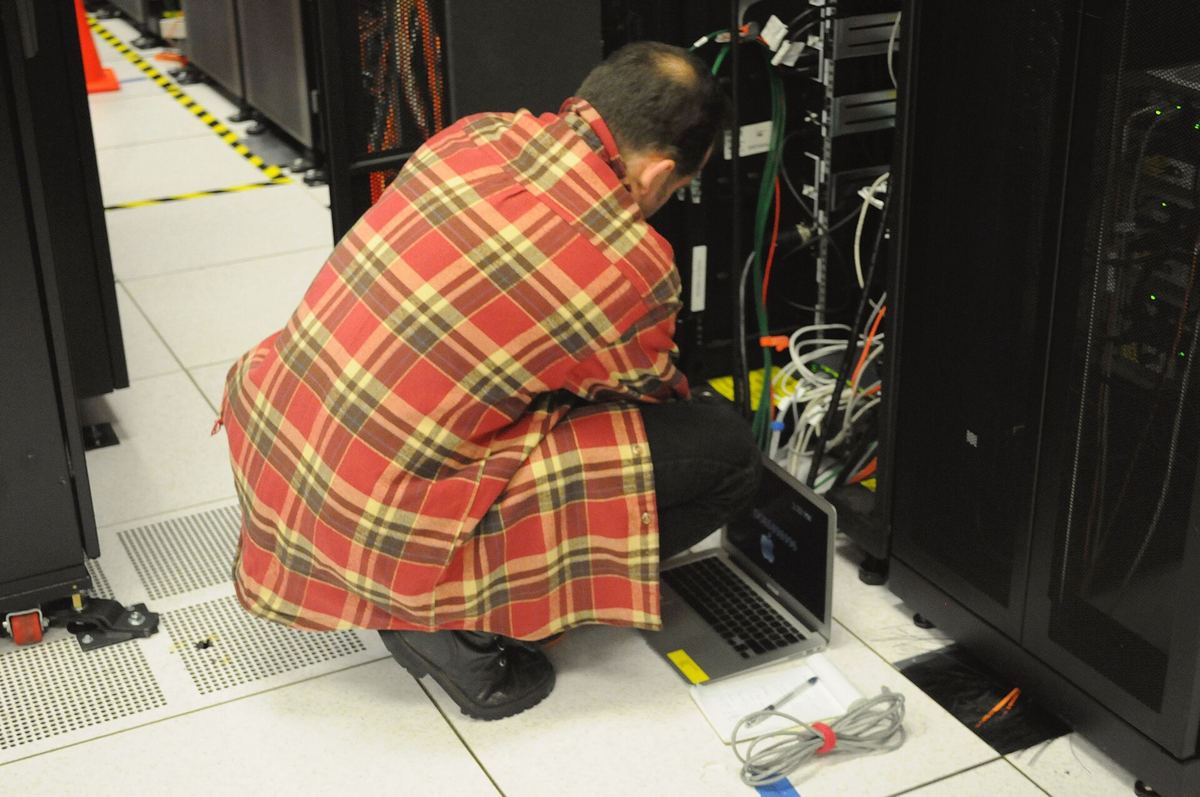 Techniker mit Laptop vor einem Serverschrank im Rechenzentrum